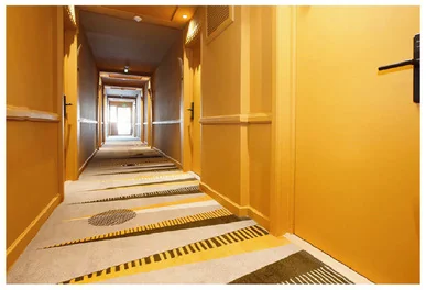 A long hotel corridor with doors and a carpeted walkway